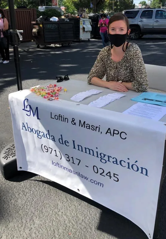 Sarah Loftin at a booth event with Loftin and Masri banner